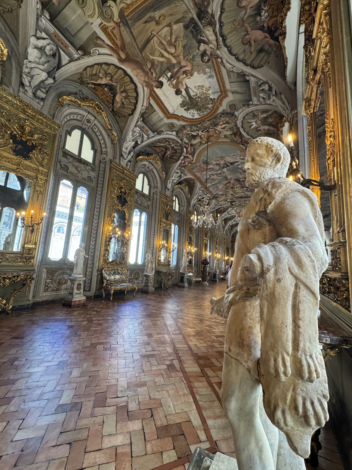 A frescoed palazzo gallery with gilded ceilings and a marble statue
