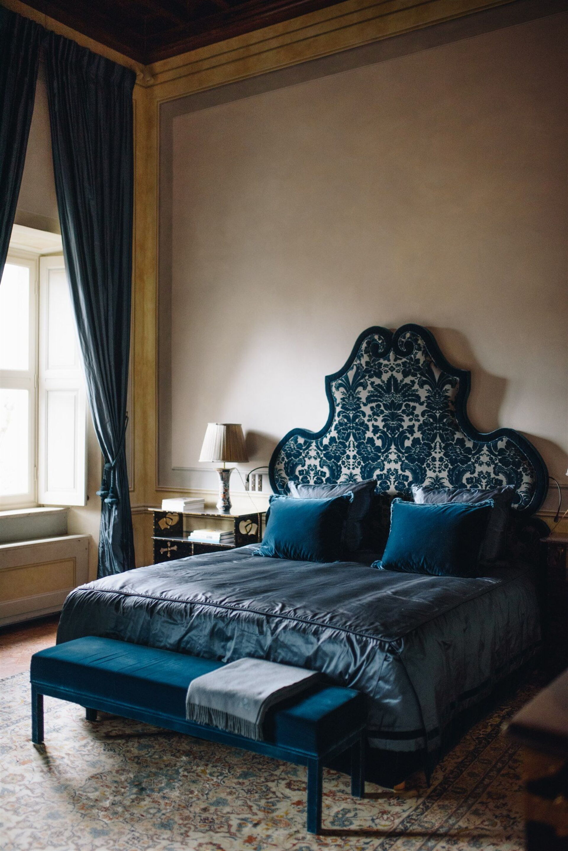 Villa Balbiano blue suite bedroom with carved damask headboard and velvet curtains overlooking Lake Como