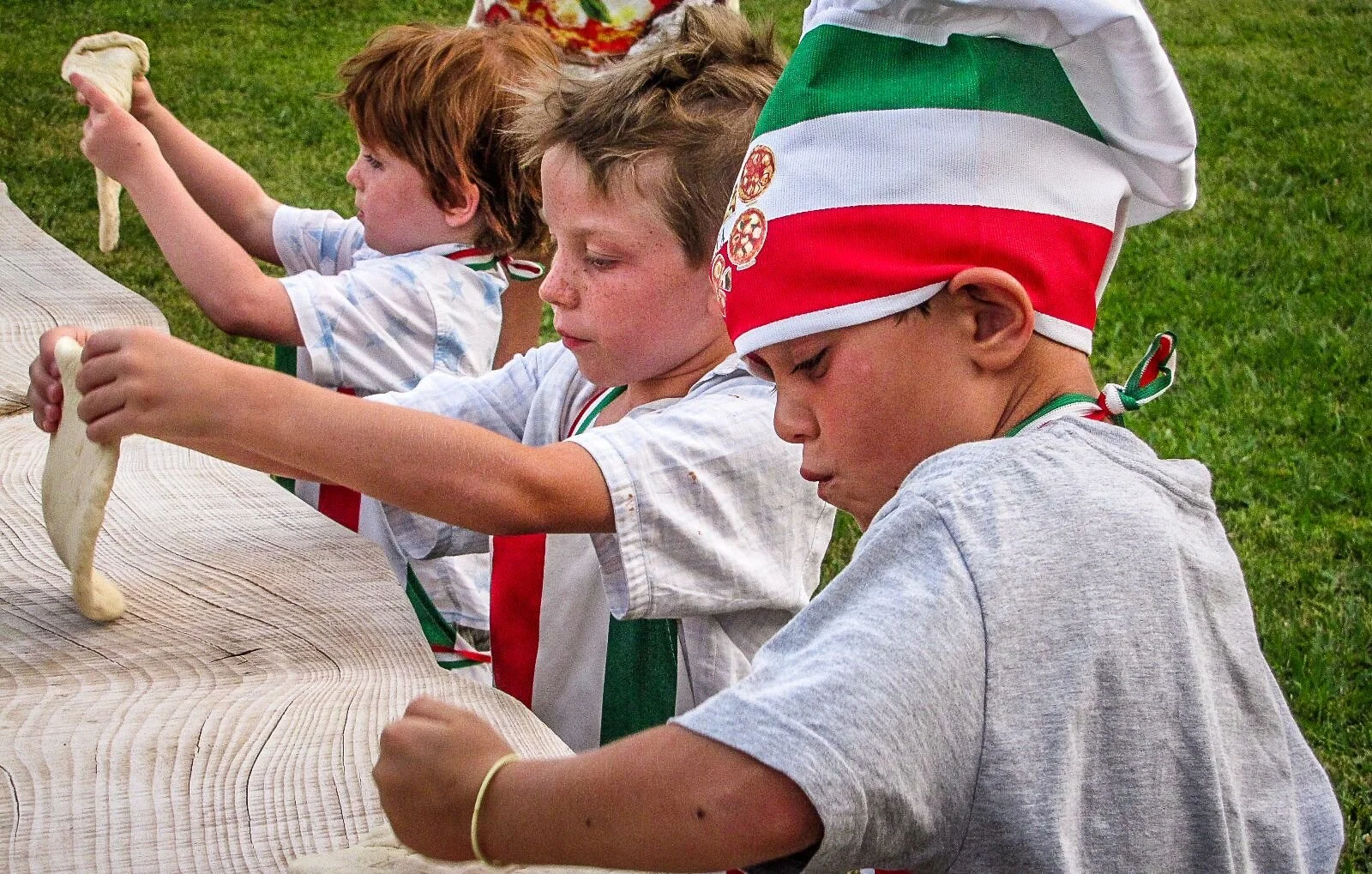 Children making pizza in tricolor chef hats