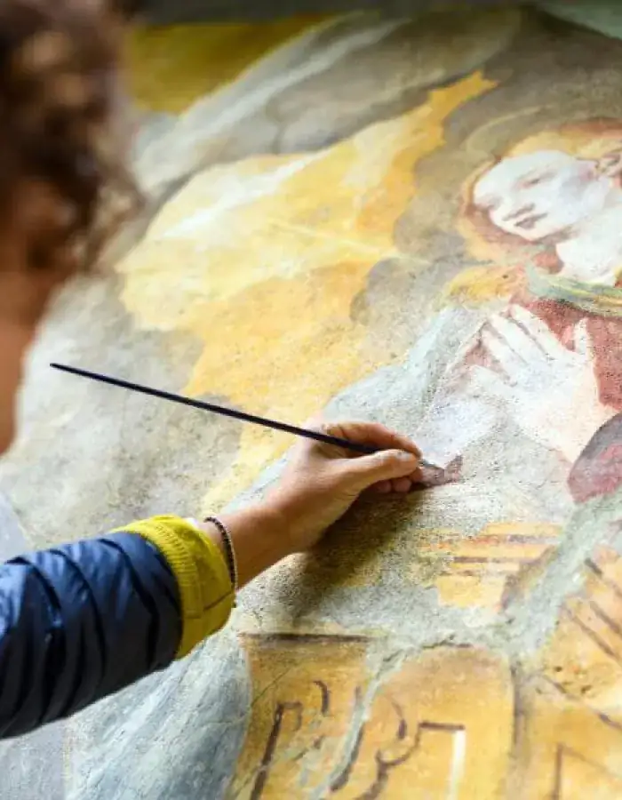 A conservator restoring a Renaissance fresco in Tuscany