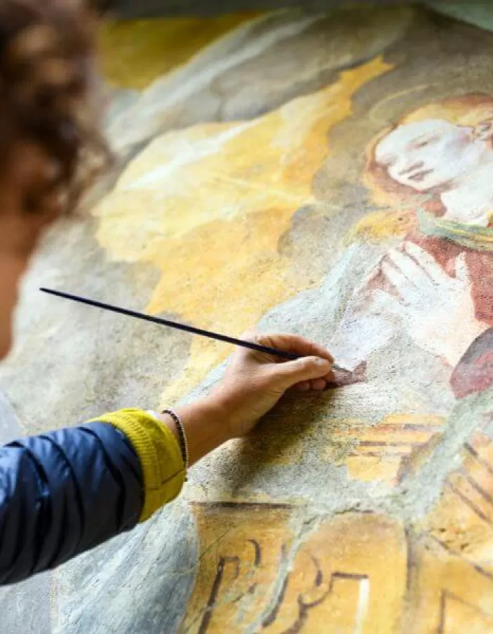 A conservator restoring a Renaissance fresco in Tuscany