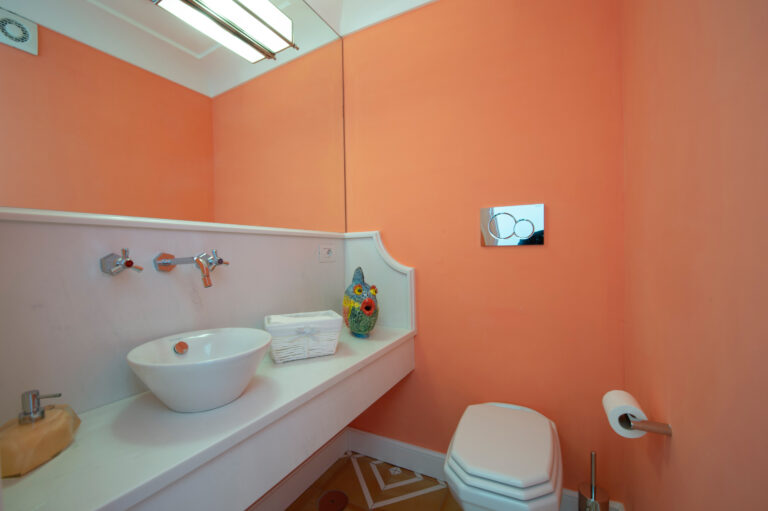 Villa Nuea — Powder room with coral wall and white pedestal basin